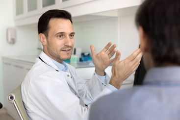 Positive male doctor talking to man at workplace