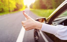 Woman inside her car gesticulate thumb up.