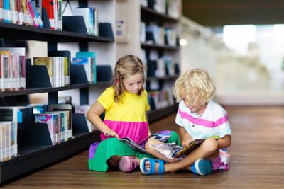 Child in school library. Kids reading books.