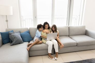 In contemporary spacious living room family using laptop