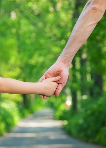 Father and child go holding hand. Selective focus.