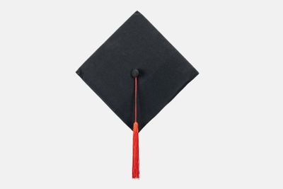 Black academic cap with red tassel isolated on white