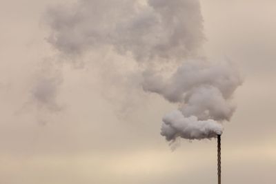 Smoke from chimney on dark cloudy sky