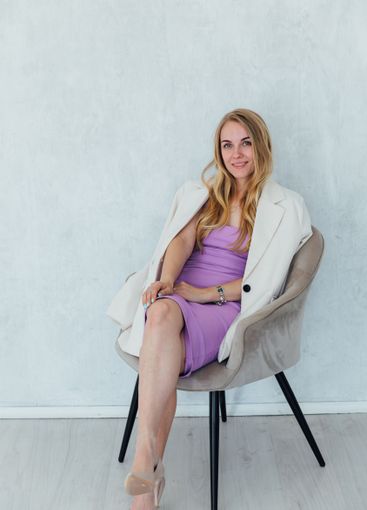 Beautiful blonde woman sitting on a chair in purple...