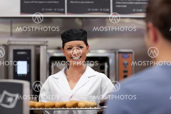 Merry young baker with baguettes