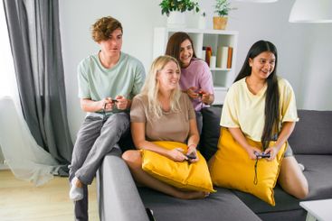 Cheerful group of friends playing video games together...
