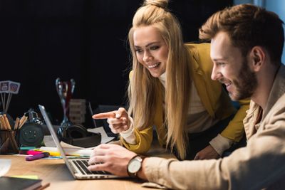 smiling female and male it specialists using laptop in...