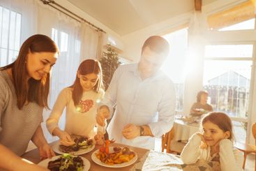 Parents and children prepare a festive lunch at home in...
