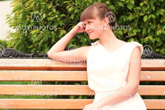 A beautiful woman is sitting on a park bench