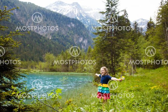 Child hiking in flower field at mountain lake