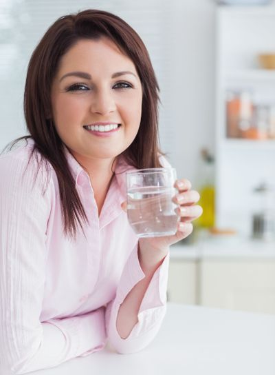 Young woman with glass of water in the kitchen