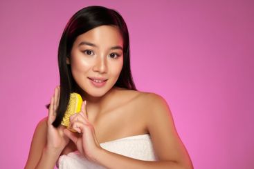 Young woman with long hair holding a yellow comb...