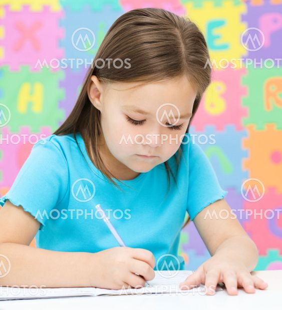Little girl is writing using a pen