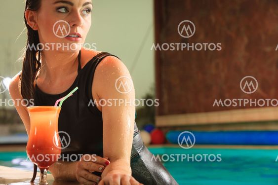 Woman with cocktail drink at swimming pool edge.