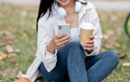 Close up of a asian woman holding a coffee cup and phone...
