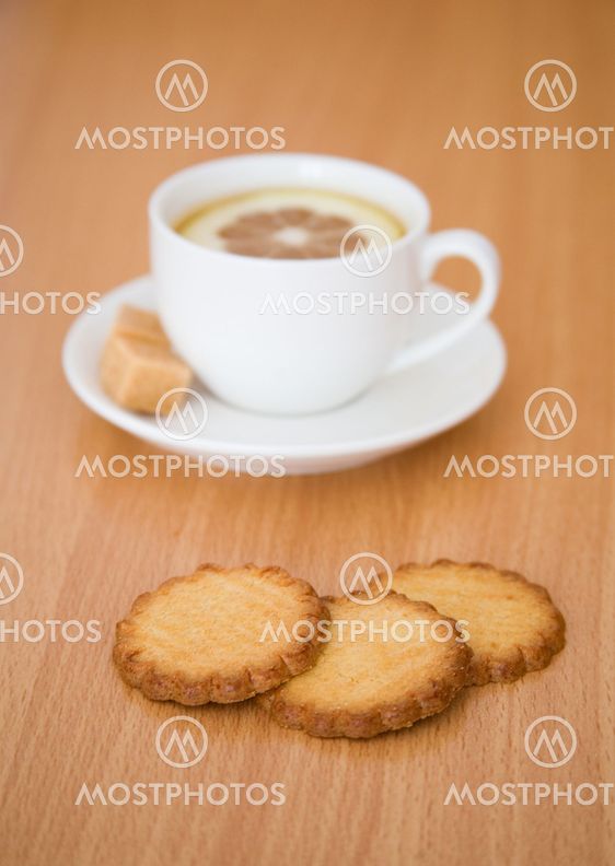 Cup of black tea with lemon, sugar and biscuits. Focus on biscuits