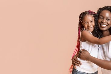 African american mother and daughter cuddling and posing...