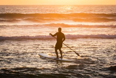 Stand up paddler silhouette at sunset
