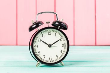 Black vintage alarm clock on wooden table