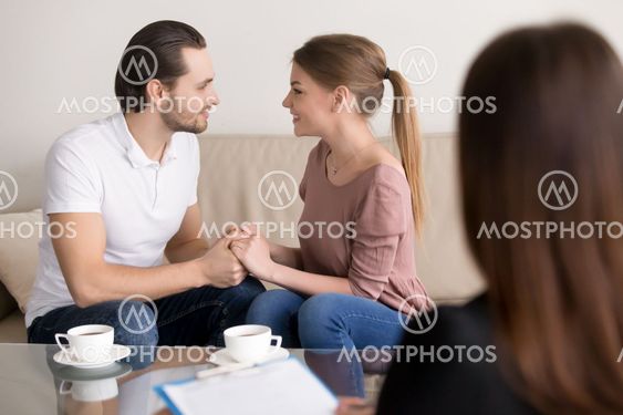 Happy smiling young couple holding hands, consulting psychologis