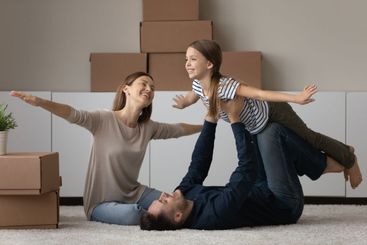 Smiling parents play with daughter on moving day