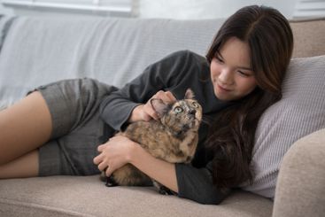 A woman lying on a couch, lovingly cuddling with her...