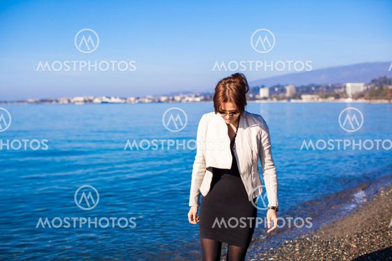 Beautiful young woman walking on the beach in winter sunny day alone