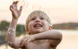 Boy playing with bubbles at sunset