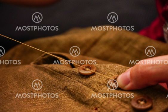 Sewing button of trousers handcraft close up view