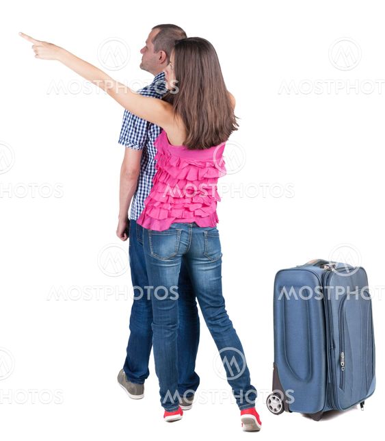 young couple traveling with suitcas and pointing at wal...