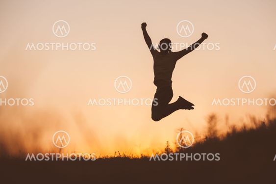 Silhouette of jumping man on sunset fiery sky background...