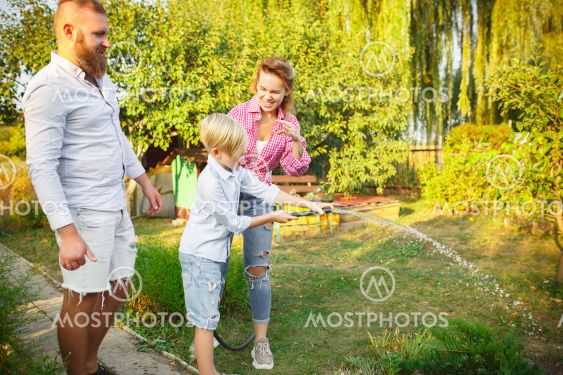 Happy family during watering plants in a garden...