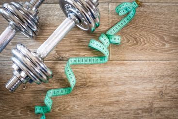 Fitness concept with dumbbells and measuring tape