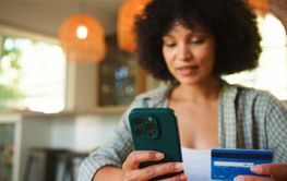 Woman Using Smartphone and Credit Card for Online...