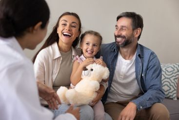 Cheerful parents and toddler girl meeting with pediatrician