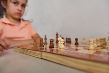 Focused young girl playing chess, concentration and...