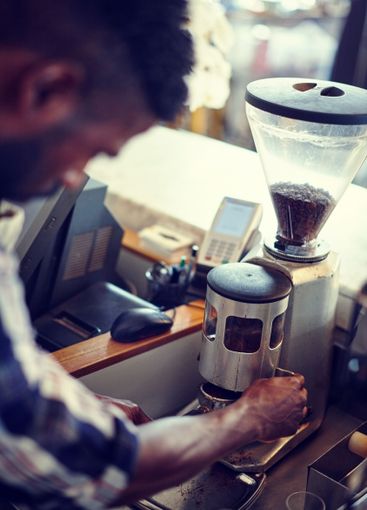 Barista, man and coffee preparation with grinder machine...