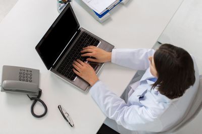 woman doctor typing on laptop at clinic