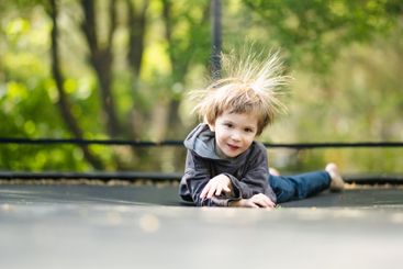 Little boy jumping on a trampoline in a backyard on warm...