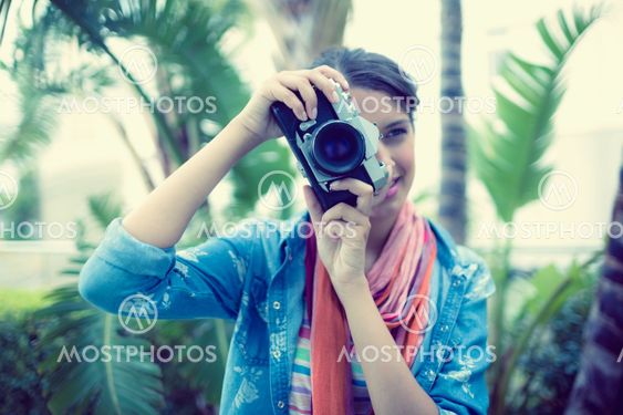 Smiling brunette taking a photo outside