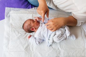 Mother playing with her one month old newborn baby son