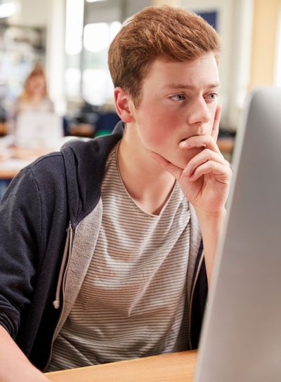 Male Student Working On Computer In College Library