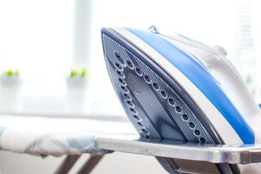 Iron on ironing board on light home interior background