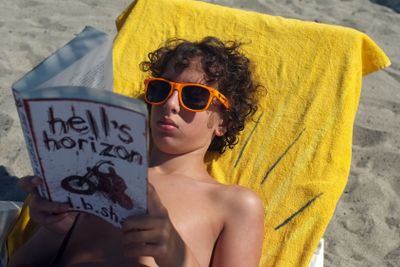 Young boy reads book on the beach