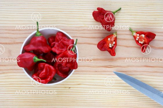 Hot chilli peppers in a bowl over a wooden table.