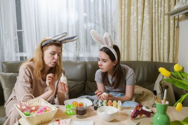 A mother and daughter wearing bunny ears decorating...
