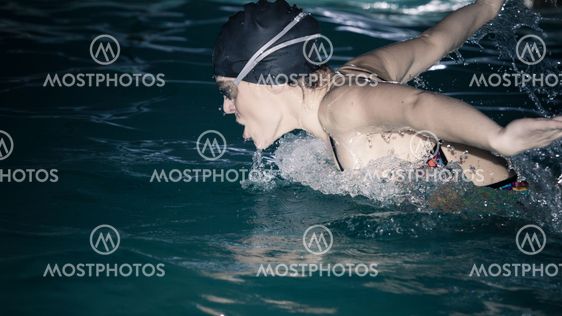 Woman athlete swimming butterfly stroke in pool.