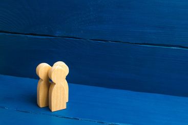 Three people stand together and talk. Three wooden...