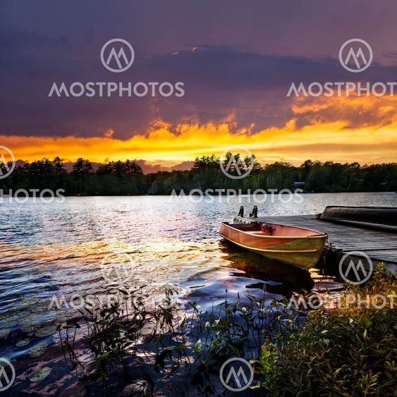Boat docked on lake at sunset