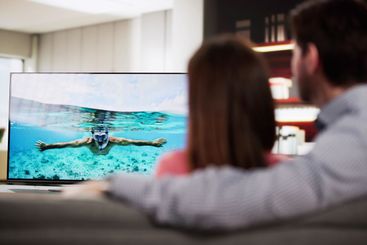 Couple Relaxing on the Sofa, Watching TV